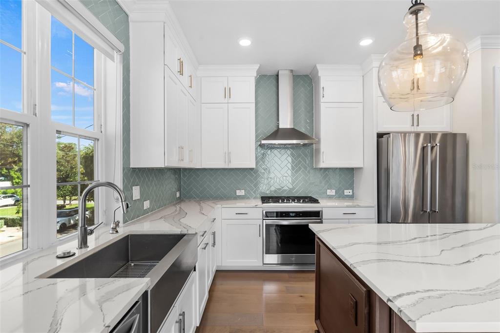 A modern kitchen features white cabinets, a herringbone tile backsplash, and a marble-topped island — 404 S MELVILLE AVENUE UNIT 4, TAMPA, FL