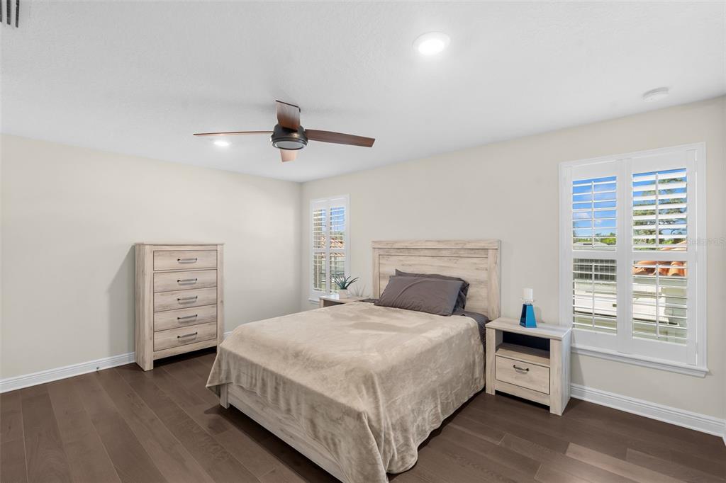 A bedroom with light wood furniture, a ceiling fan, and white plantation shutters on windows — 404 S MELVILLE AVENUE UNIT 4, TAMPA, FL