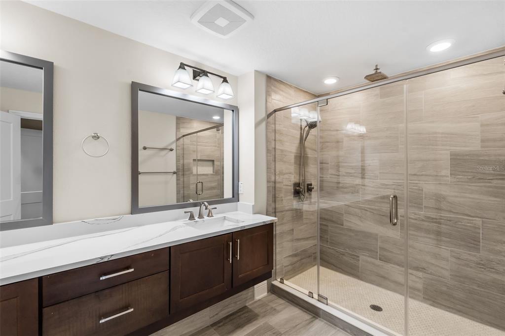 A modern bathroom features a dark wood vanity, white countertop, and a glass-enclosed tiled shower — 404 S MELVILLE AVENUE UNIT 4, TAMPA, FL