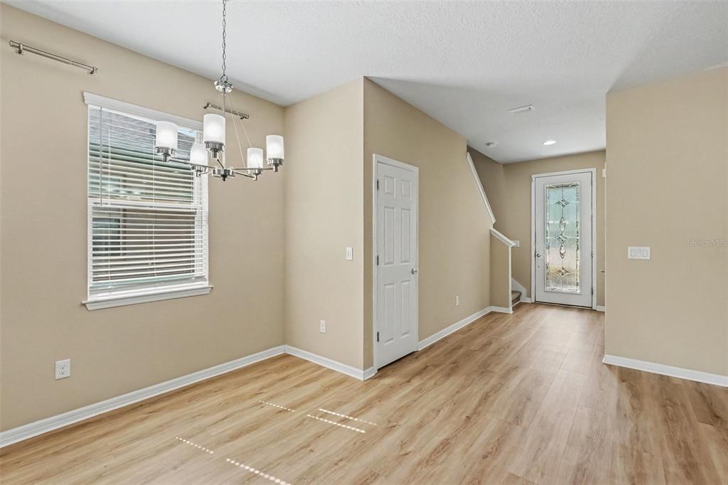 A dining area features light wood-look flooring, a chandelier, a window, and a white door — 5117 LEVANA STREET, PALMETTO, FL