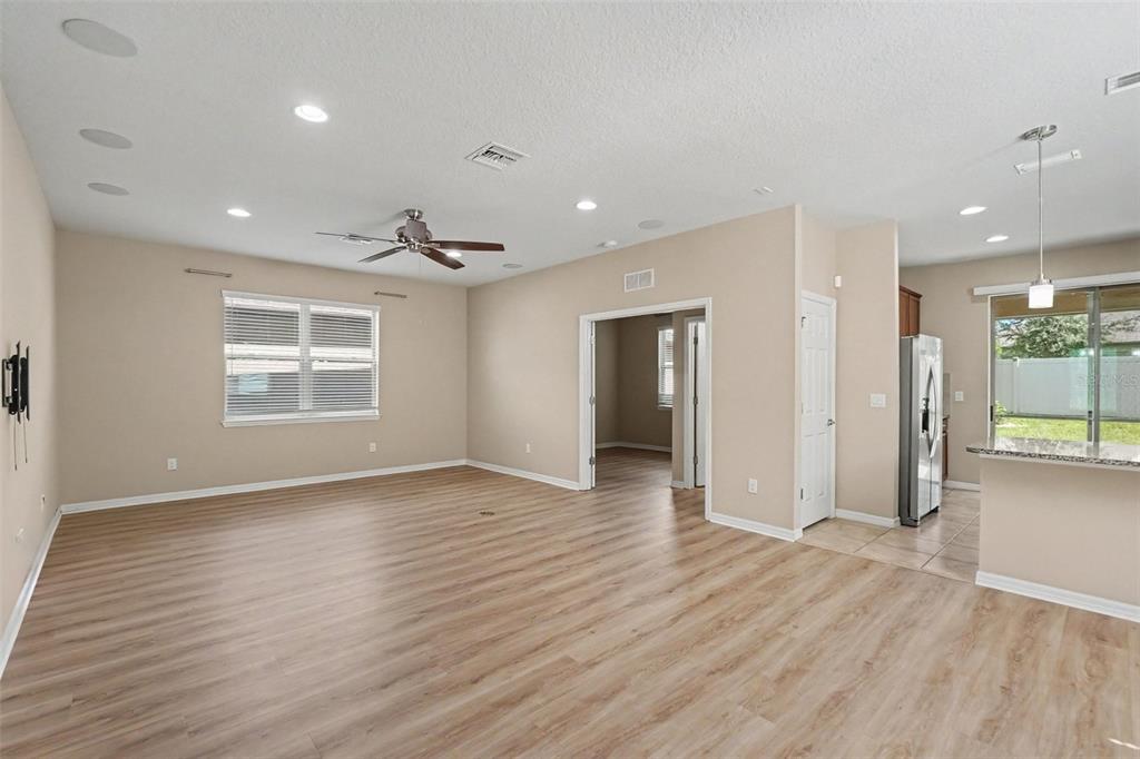 An open-concept living room with light wood-look flooring, recessed lighting, and a ceiling fan — 5117 LEVANA STREET, PALMETTO, FL
