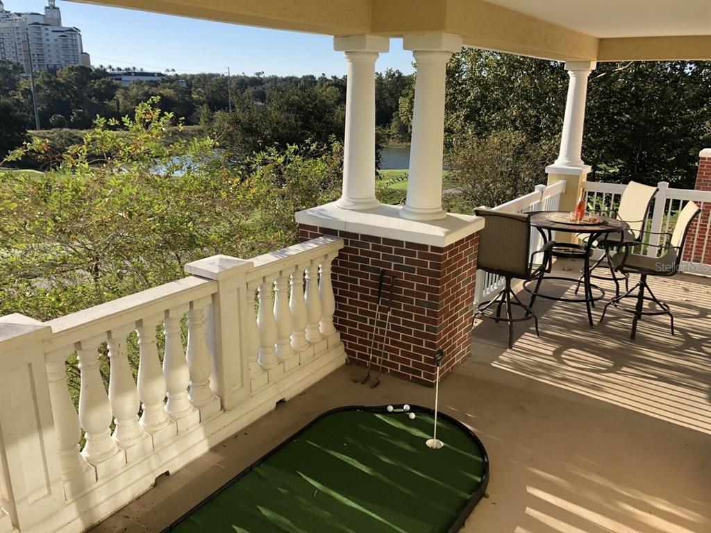 A multi-story residential building with balconies and a cupola sits above a grassy hill — 7604 CABANA CT UNIT 303, REUNION, FL