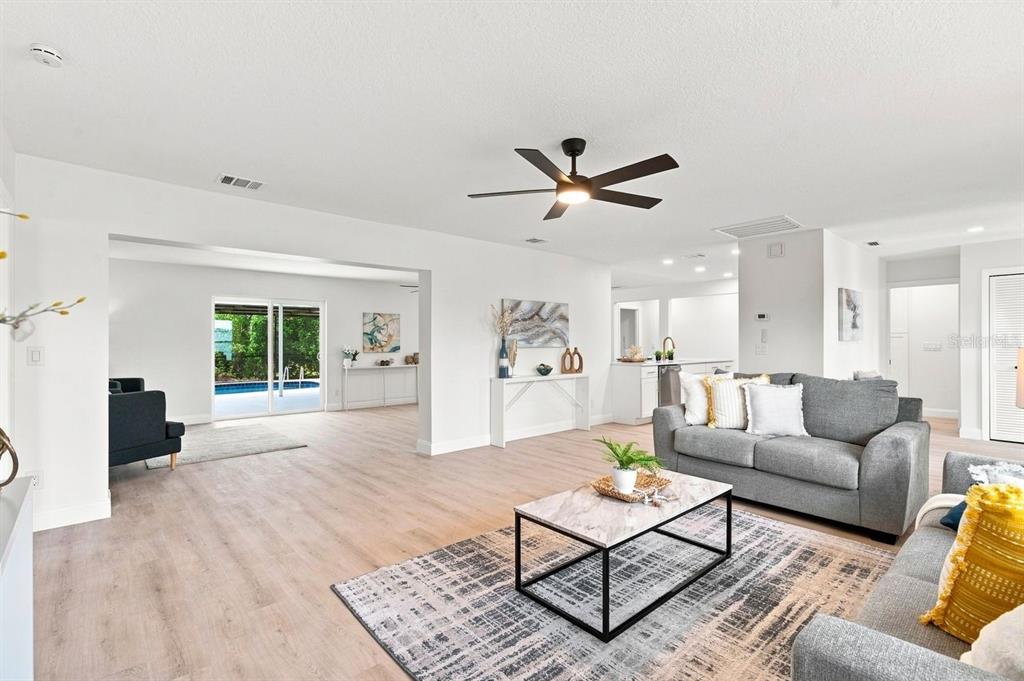 A bright living room features light wood flooring, a gray sofa, and a ceiling fan — 212 GIOTTO DRIVE, NOKOMIS, FL