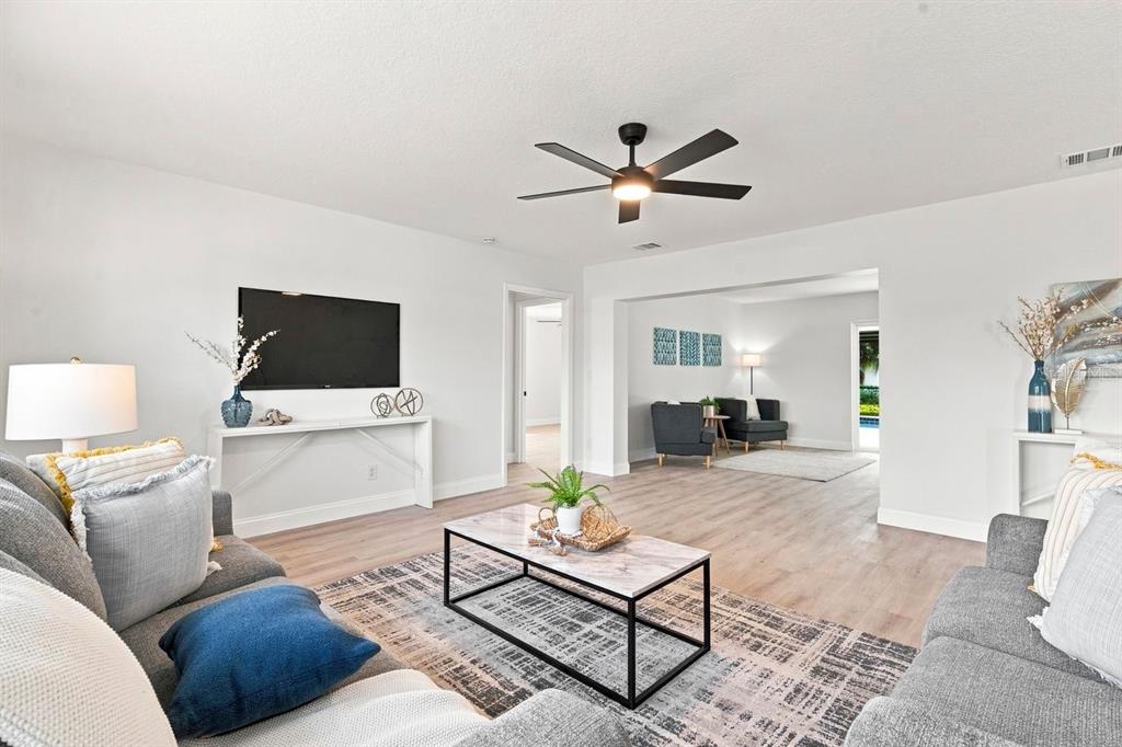 A living room features light wood flooring, a ceiling fan, and a marble-topped coffee table — 212 GIOTTO DRIVE, NOKOMIS, FL