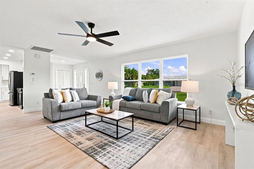 A living room features gray sofas, a patterned area rug, and a ceiling fan — 212 GIOTTO DRIVE, NOKOMIS, FL
