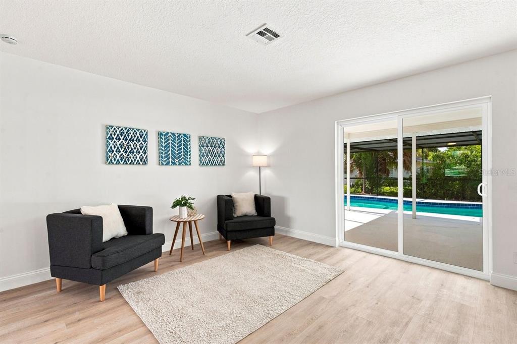 A living room with two black chairs, a small table, and a sliding glass door — 212 GIOTTO DRIVE, NOKOMIS, FL