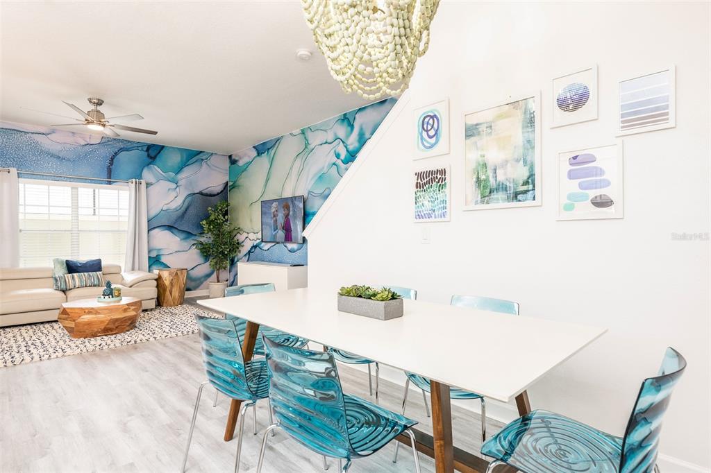 A dining area with blue acrylic chairs sits next to a living room with blue wallpaper — 8938 CUBAN PALM ROAD, KISSIMMEE, FL