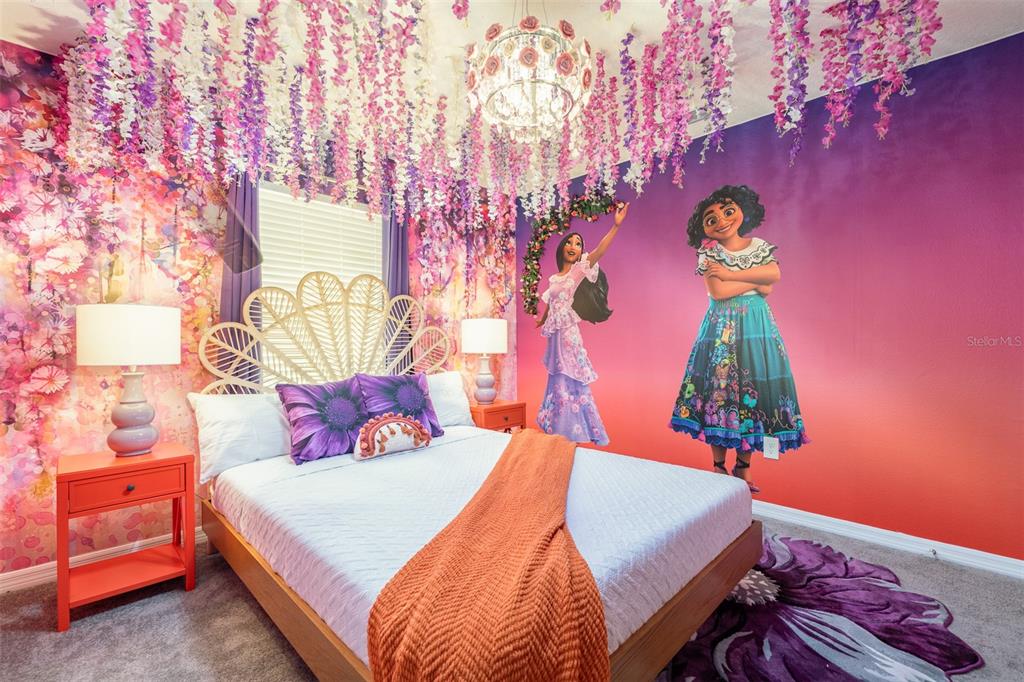 A bedroom features Encanto-themed wall murals, hanging floral decorations, a peacock-style headboard, and orange furniture — 8938 CUBAN PALM ROAD, KISSIMMEE, FL