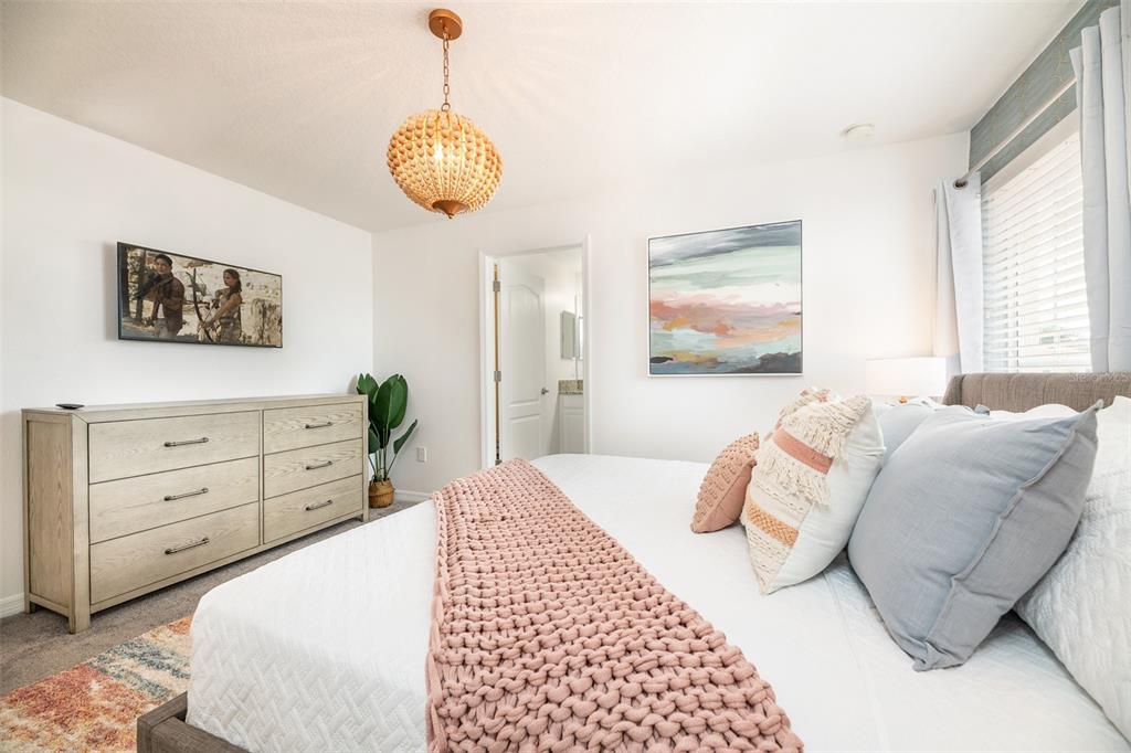 A bedroom features a light wood dresser, a beaded chandelier, and a bed with pink accents — 8938 CUBAN PALM ROAD, KISSIMMEE, FL