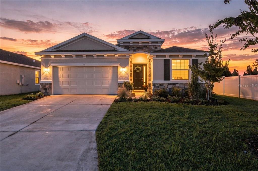 A single-story house with a two-car garage and stone accents at sunset — 3804 N MARYLAND AVENUE, PLANT CITY, FL