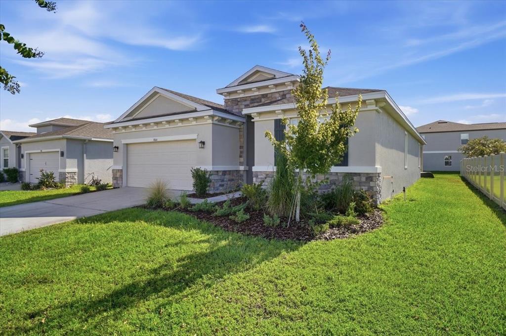 A single-story suburban house with a tan stucco facade, stone accents, and a two-car garage — 3804 N MARYLAND AVENUE, PLANT CITY, FL