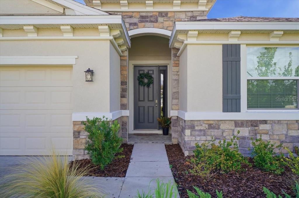 The exterior of a house features a stone facade, a gray front door, and a walkway — 3804 N MARYLAND AVENUE, PLANT CITY, FL