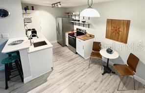 A kitchen features white cabinetry, stainless steel appliances, a breakfast bar, and a small dining area — 10263 GANDY BOULEVARD N UNIT 311, ST PETERSBURG, FL