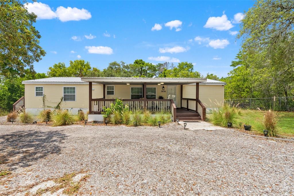 A kitchen features white cabinets, stainless steel appliances, a center island, and wood-look flooring — 7876 RIDGE ROAD, WEEKI WACHEE, FL