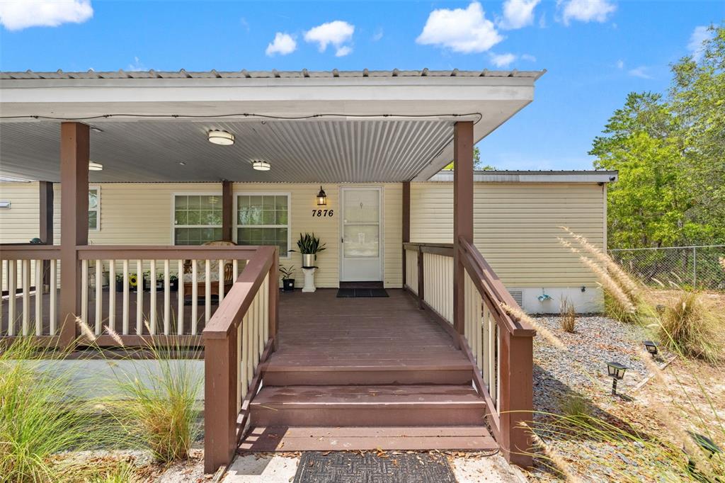 A single-story manufactured home with a large covered front porch and a gravel driveway — 7876 RIDGE ROAD, WEEKI WACHEE, FL
