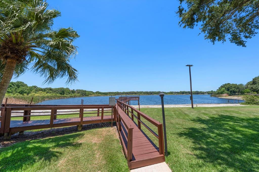 A wooden walkway leads to a dock extending into a lake under a clear sky — 2069 LAKEVIEW DRIVE, CLEARWATER, FL