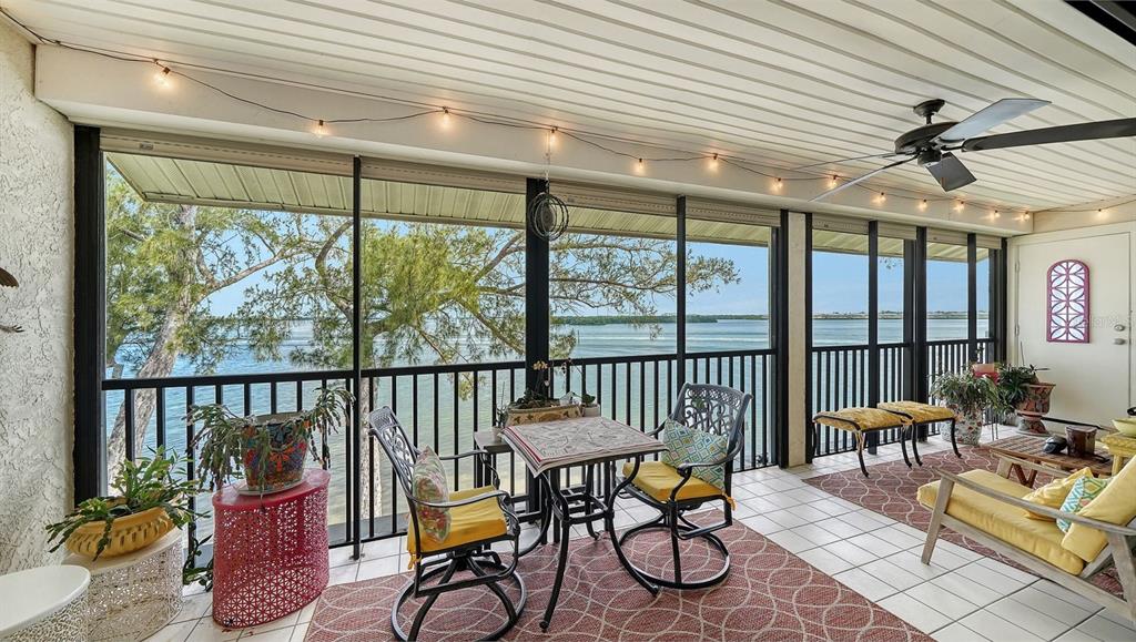 A screened-in porch features tile flooring, outdoor furniture, and a view of the water — 3840 MARINERS WAY UNIT 524A, CORTEZ, FL