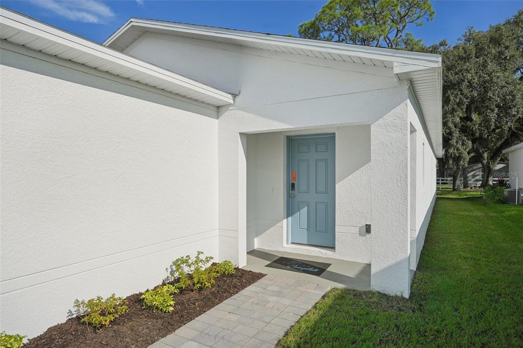 A white single-story house with a blue front door, a garage, and a paved walkway — 2073 GOLDEN BEAK DRIVE, EAGLE LAKE, FL