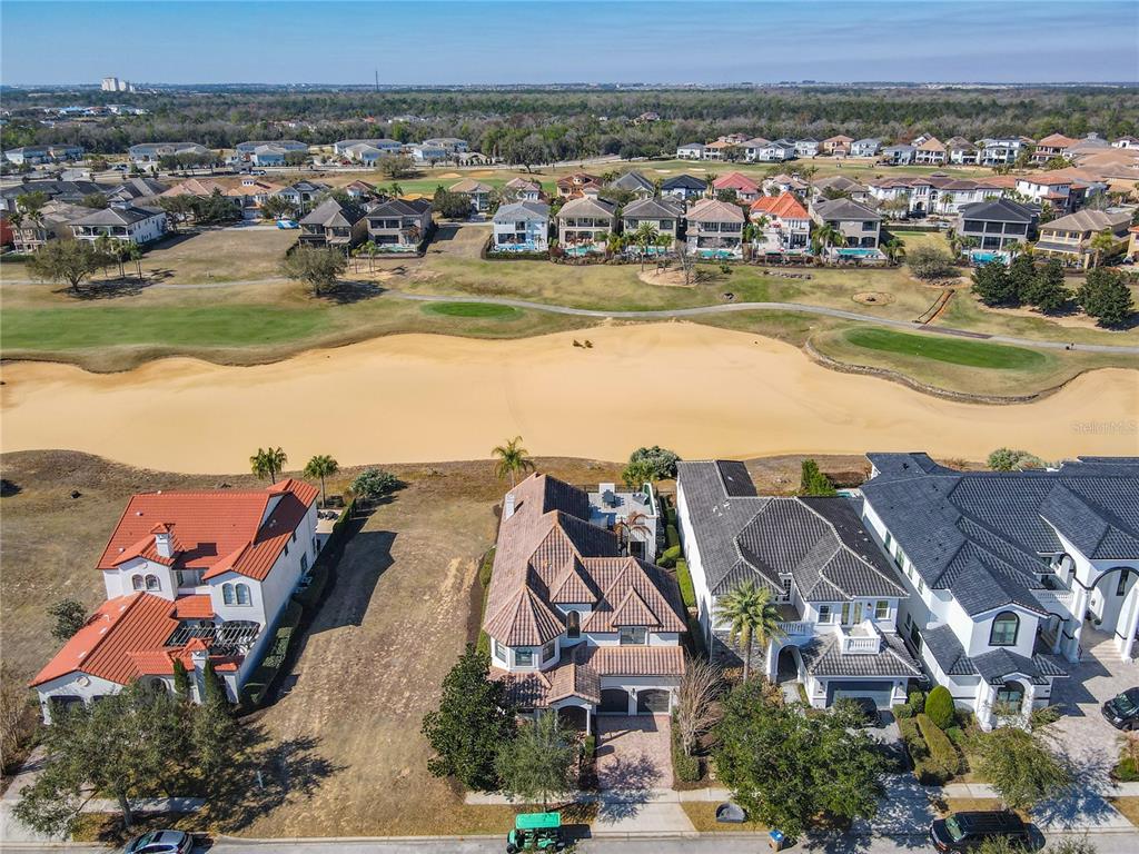 An aerial view shows three houses bordering a large sand bunker on a golf course — 535 MUIRFIELD LOOP, REUNION, FL