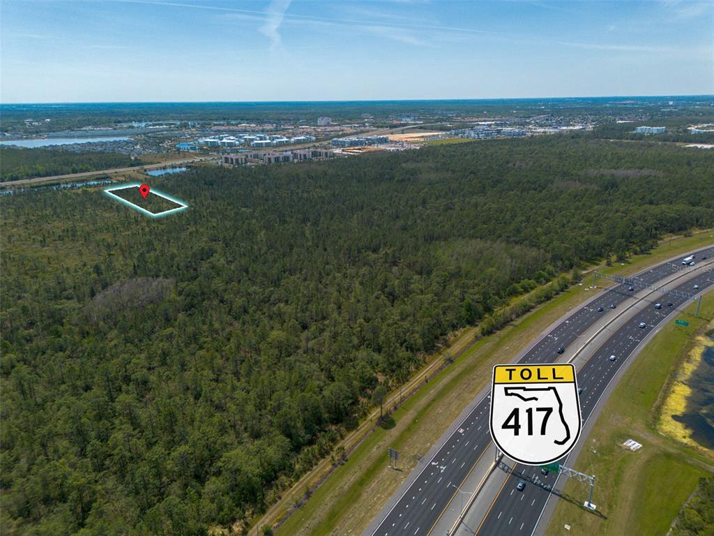 An aerial view shows a wooded lot marked with a pin near a toll highway — SR-535, ORLANDO, FL