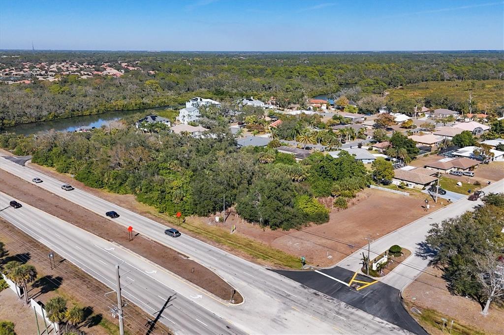 An aerial view shows a vacant corner lot adjacent to a highway and residential neighborhood — 2099 S TAMIAMI TRAIL, OSPREY, FL
