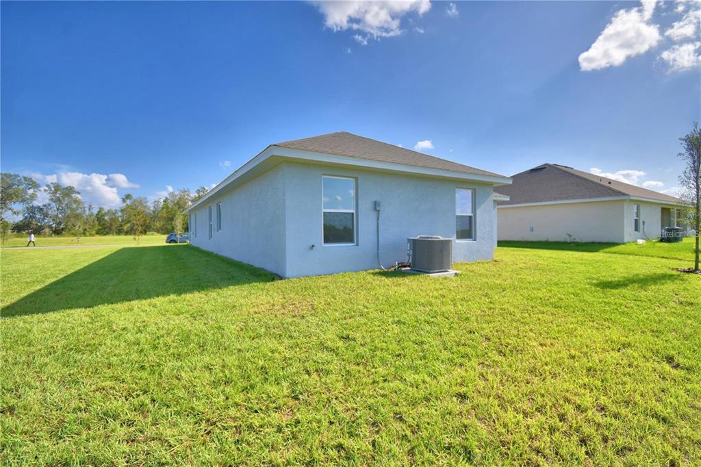 The exterior of a light-colored house features a grassy yard and an air conditioning unit — 3652 LINDBERGH STREET, LAKELAND, FL