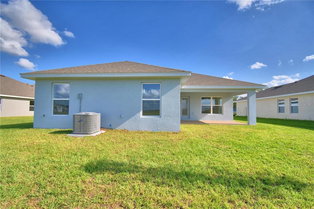 The rear exterior of a light blue house features a covered patio and an air conditioner — 3652 LINDBERGH STREET, LAKELAND, FL