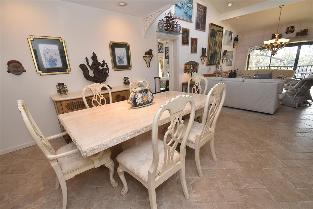 A dining room with a stone table, white chairs, and numerous wall-mounted art pieces — 1633 BOATHOUSE CIRCLE UNIT HA231, SARASOTA, FL