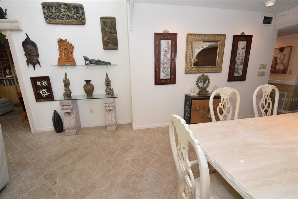 A dining room features a stone table, white chairs, and walls decorated with Asian-inspired art — 1633 BOATHOUSE CIRCLE UNIT HA231, SARASOTA, FL