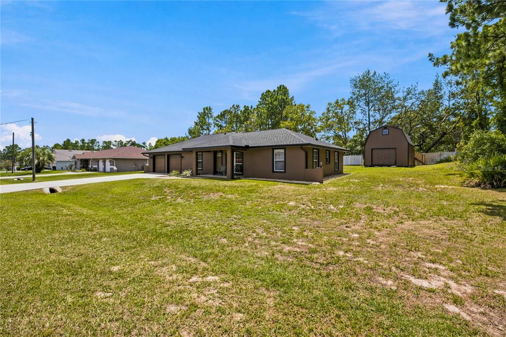 A brown single-story house with a detached shed sits on a large grassy lot — 24 FIR TRAIL PASS, OCALA, FL
