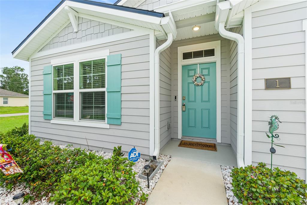 The exterior of a house features light gray siding, a teal front door, and shutters — 1 RICHFIELD PLACE, PALM COAST, FL