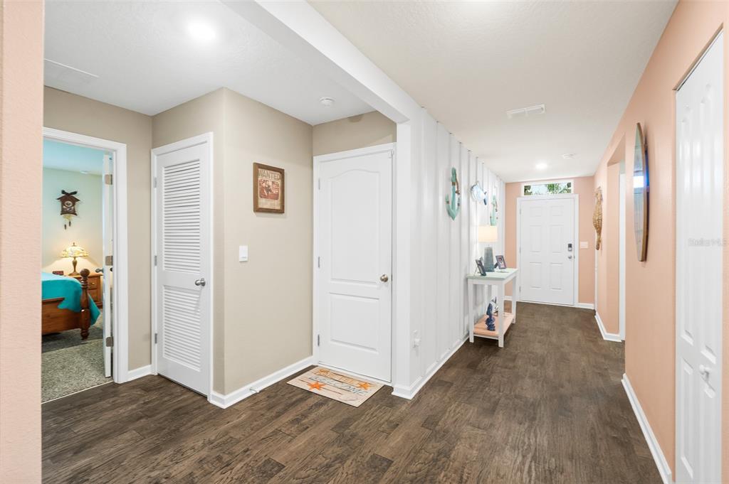 A bright entryway features dark wood-look flooring, white doors, and a coastal-themed console table — 1 RICHFIELD PLACE, PALM COAST, FL