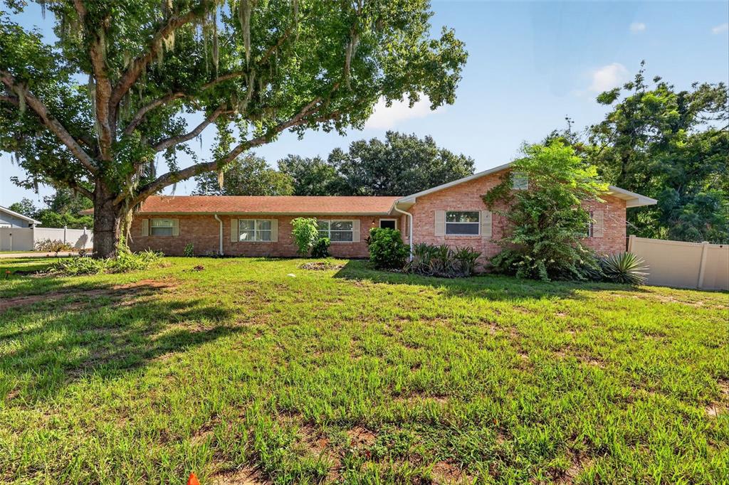 A single-story brick house with a large oak tree and a grassy front yard — 5 HERMOSA DRIVE, EUSTIS, FL