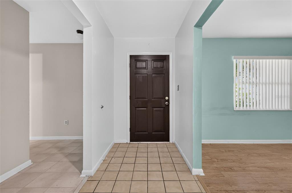An entryway with a dark brown door, tiled floor, and adjacent living spaces — 5 HERMOSA DRIVE, EUSTIS, FL