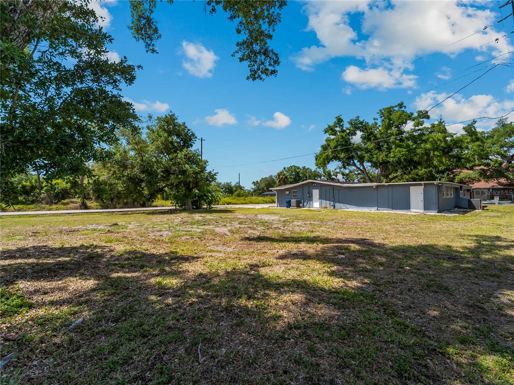 A large, grassy lot sits in front of a long, single-story gray building — SHAMROCK DRIVE, VENICE, FL