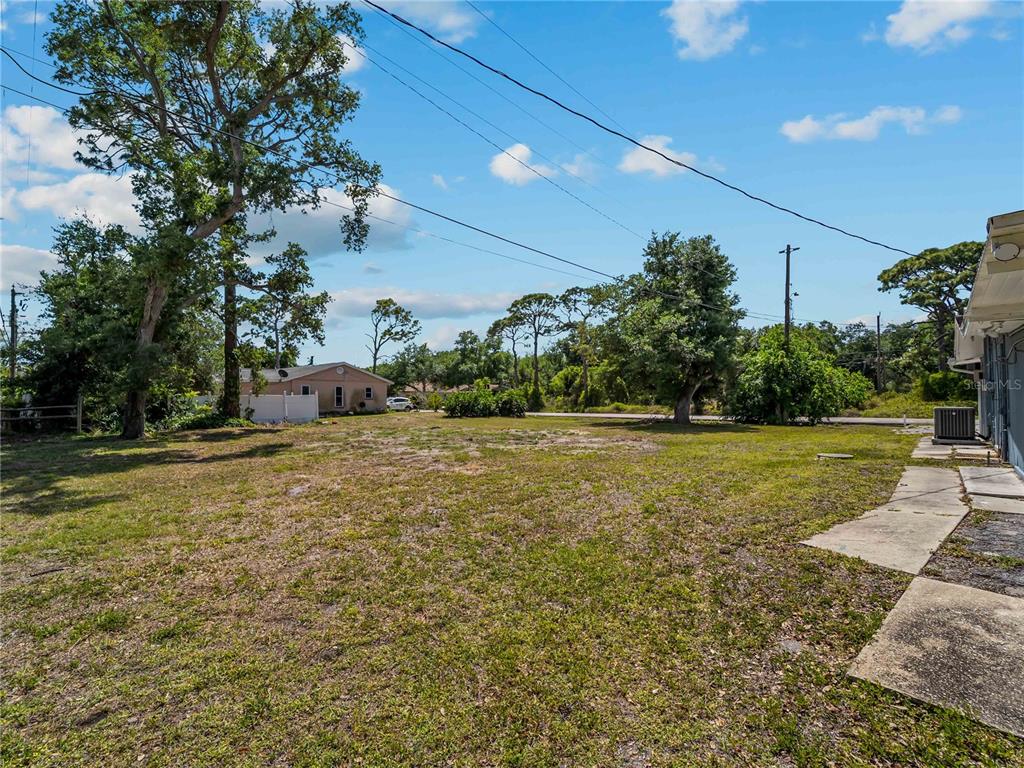 A large, grassy backyard features several mature trees and a view of a neighboring house — SHAMROCK DRIVE, VENICE, FL