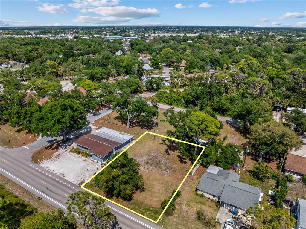 An aerial view shows a vacant rectangular lot outlined in yellow between two houses — SHAMROCK DRIVE, VENICE, FL