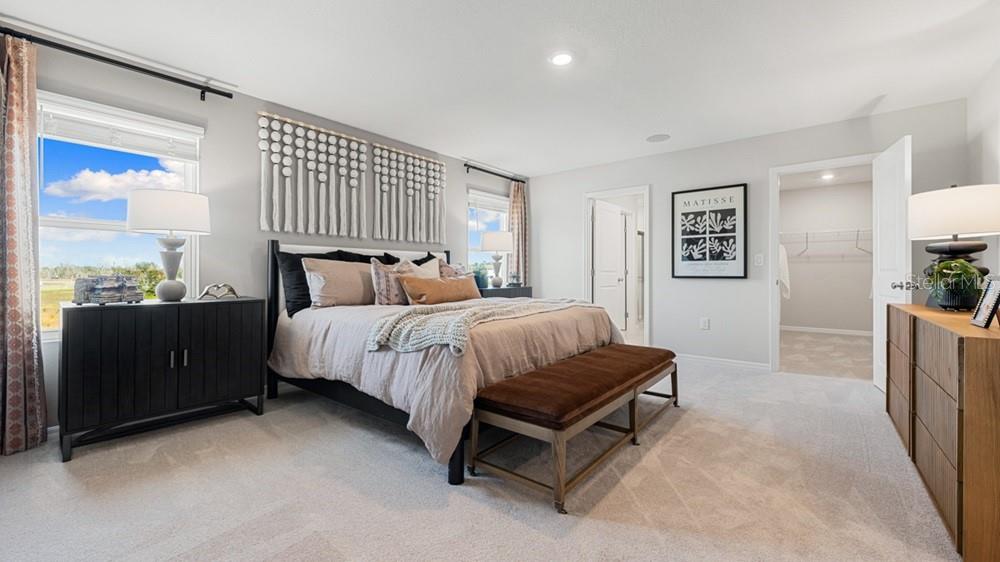 A bedroom features a bed with a brown bench, two dressers, and a walk-in closet — 13827 SHELLMORE AVENUE, PALMETTO, FL