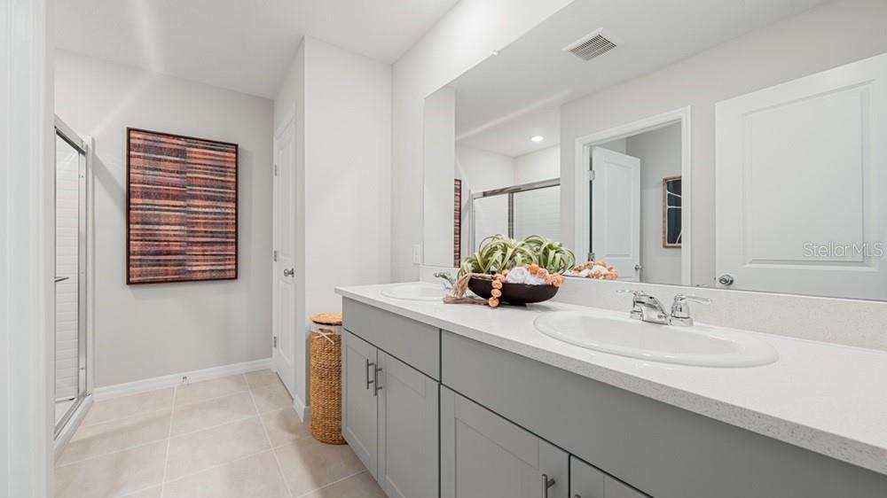 A bathroom features a double vanity with gray cabinets, white countertops, and a large mirror — 13827 SHELLMORE AVENUE, PALMETTO, FL