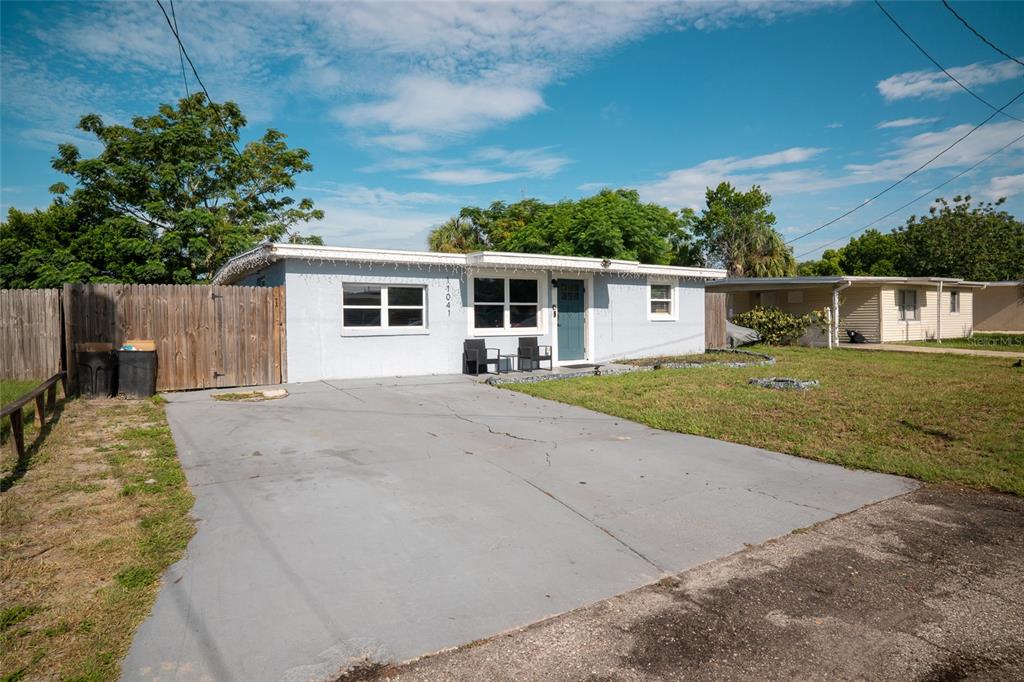 A single-story house with a gray exterior, a concrete driveway, and a wooden fence — 11041 TAFT DRIVE, PORT RICHEY, FL