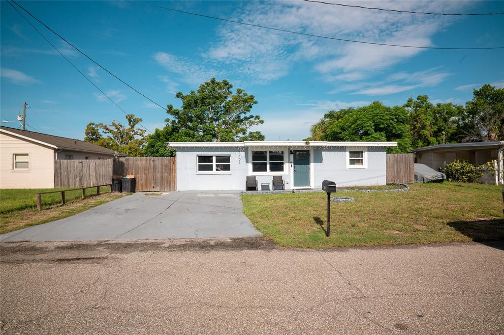 A single-story house with a light blue exterior, a concrete driveway, and a fenced yard — 11041 TAFT DRIVE, PORT RICHEY, FL