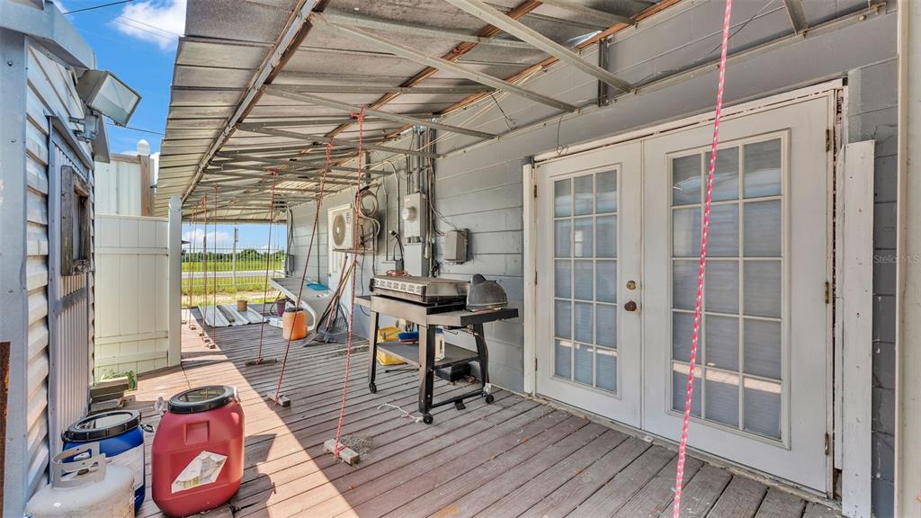 A wooden deck with a metal awning, a grill, and French doors on a house exterior — 2999 US HIGHWAY 92, WINTER HAVEN, FL