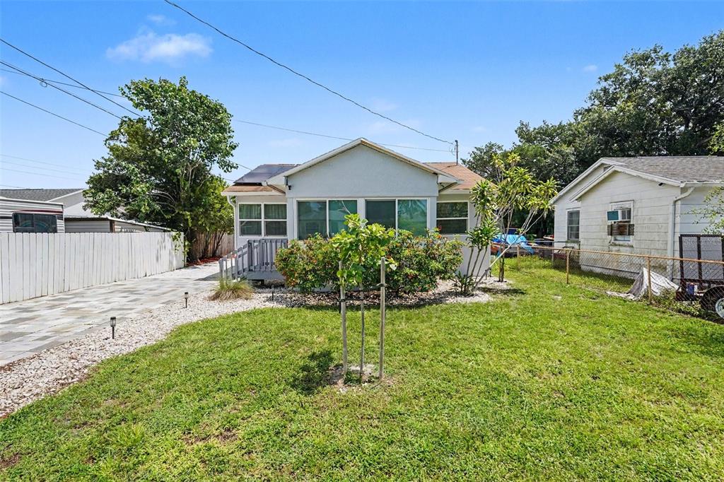 A light-colored single-story house with a screened porch, a front lawn, and a gravel driveway — 5709 35TH STREET N, ST PETERSBURG, FL