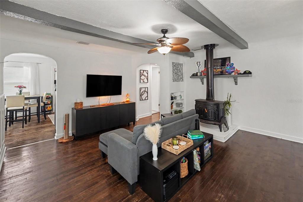 A living room features a wood-burning stove, dark hardwood floors, and a grey sofa — 5709 35TH STREET N, ST PETERSBURG, FL