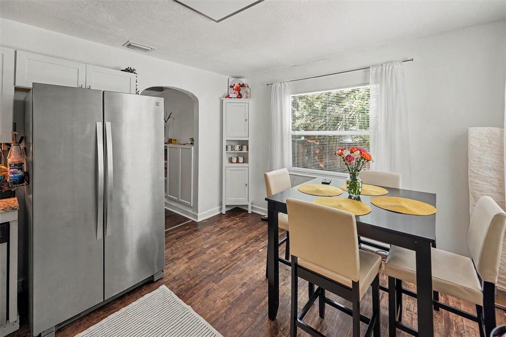 A dining area features a dark table, four chairs, a stainless refrigerator, and wood flooring — 5709 35TH STREET N, ST PETERSBURG, FL