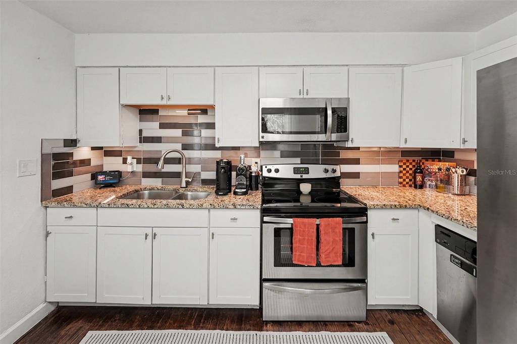 A kitchen with white cabinets, stainless steel appliances, granite countertops, and a tiled backsplash — 5709 35TH STREET N, ST PETERSBURG, FL