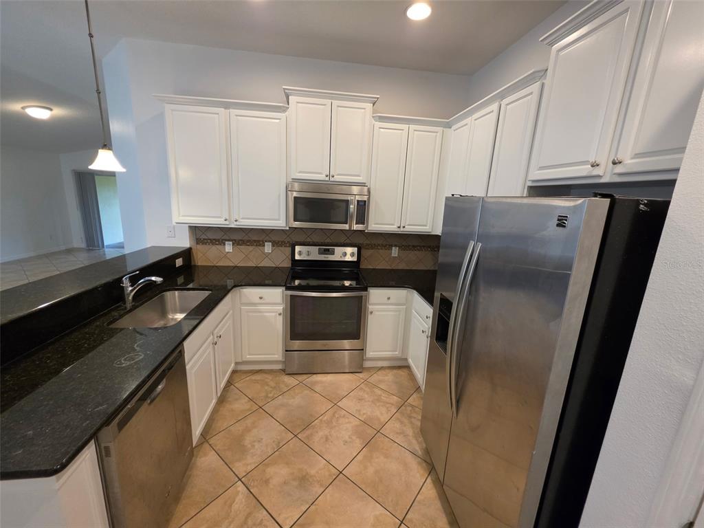 A bathroom features a vanity with a dark countertop, a toilet, and a tiled bathtub — 12120 TRIPLETAIL LANE, ORLANDO, FL