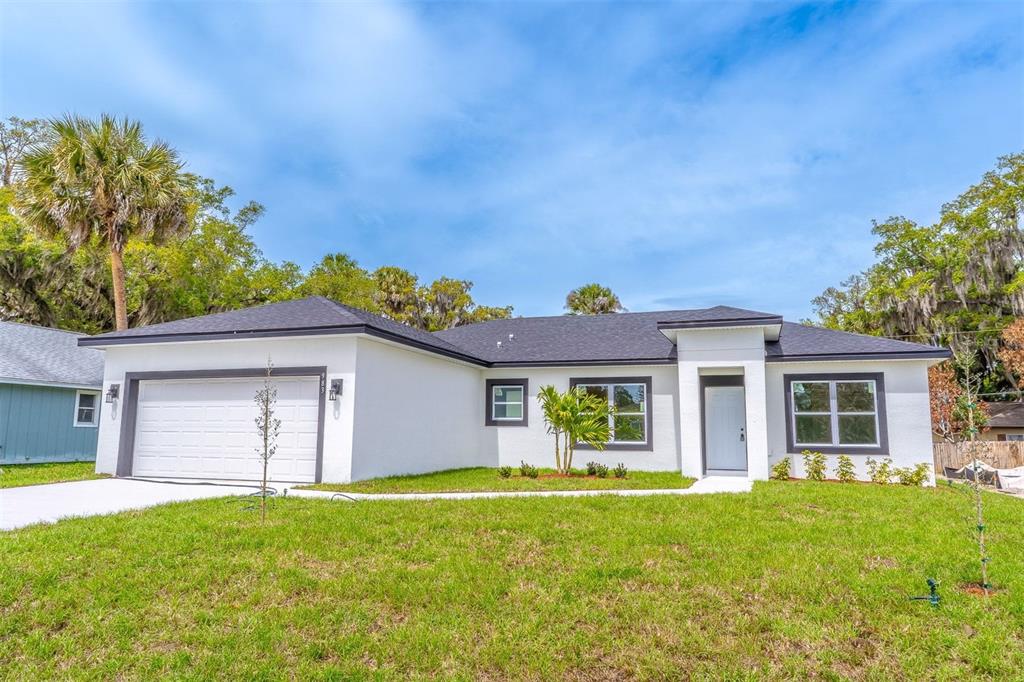 A white, single-story house with a dark roof, garage, and front entrance under a blue sky — 983 PACE DRIVE NW, PALM BAY, FL