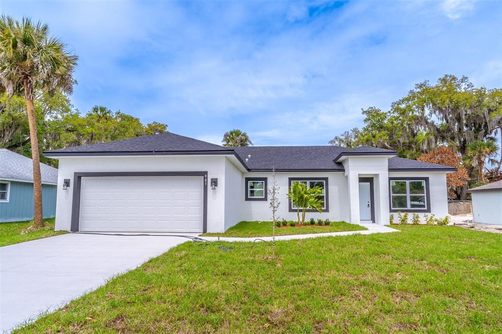 A single-story white house with a dark roof, garage, and front entrance on a lawn — 983 PACE DRIVE NW, PALM BAY, FL