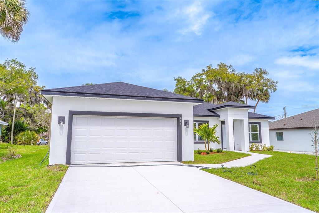 A white single-story house with a two-car garage and a concrete driveway — 983 PACE DRIVE NW, PALM BAY, FL